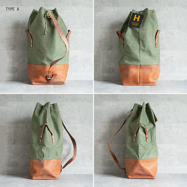 Olive drab canvas duffel bag with tan leather bottom, drawstring top, buckles