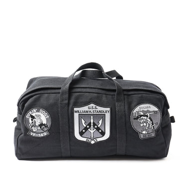 Black duffel bag with top handle and front patches, including U.S.S. William H. Stanley