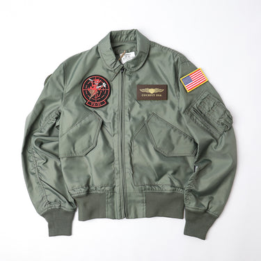 Sage green flight jacket with front zip, top chest patch, and US flag sleeve patch