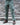 Teal-green cargo pants with side pockets and thigh flap pockets, worn with boots.