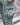 Teal-green cargo pants with lower side cargo pocket and woven brand patch detail.