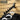 Black slant-arm wall rack with hooks holding hangers and shirts