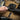 Black hook-and-loop equipment strap with textured fastening, being adjusted by hand