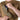 Tan sling backpack front pocket close-up with zipper and quick-access opening.