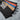 Two-tone rain shell jacket with tan body and black lower panels, blue stripe