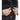 Black tactical MOLLE vest close-up showing hands adjusting side webbing strap