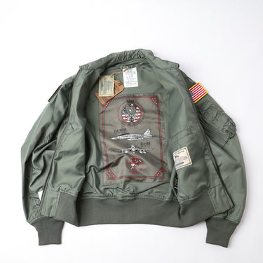 Sage green flight jacket open back with large graphic patch and US flag sleeve patch