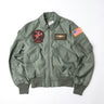 Sage green flight jacket with front zip, top chest patch, and US flag sleeve patch