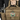 Tan tactical chest rig close-up with cartoon patch and side pocket holding a canister