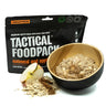 Black freeze-dried meal pouch with oatmeal and apples, wooden bowl and dried flakes