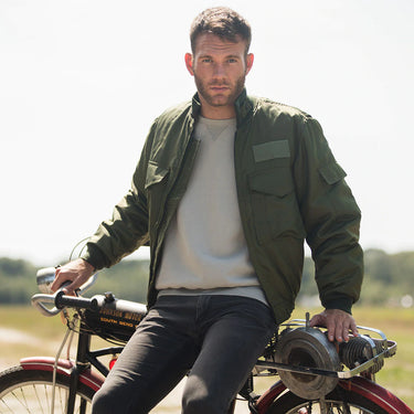 Olive field jacket worn open over a T-shirt with flap pockets and zipper front